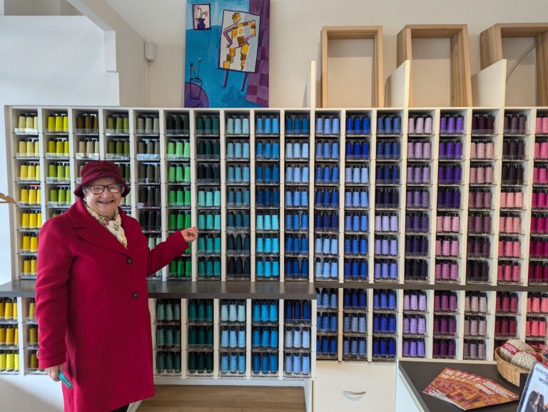 Terrie in front of a large wall of coloured yarn Australia