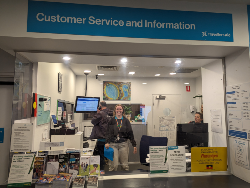 Reception desk with lady smiling at the camera, at travellers aid southern cross
