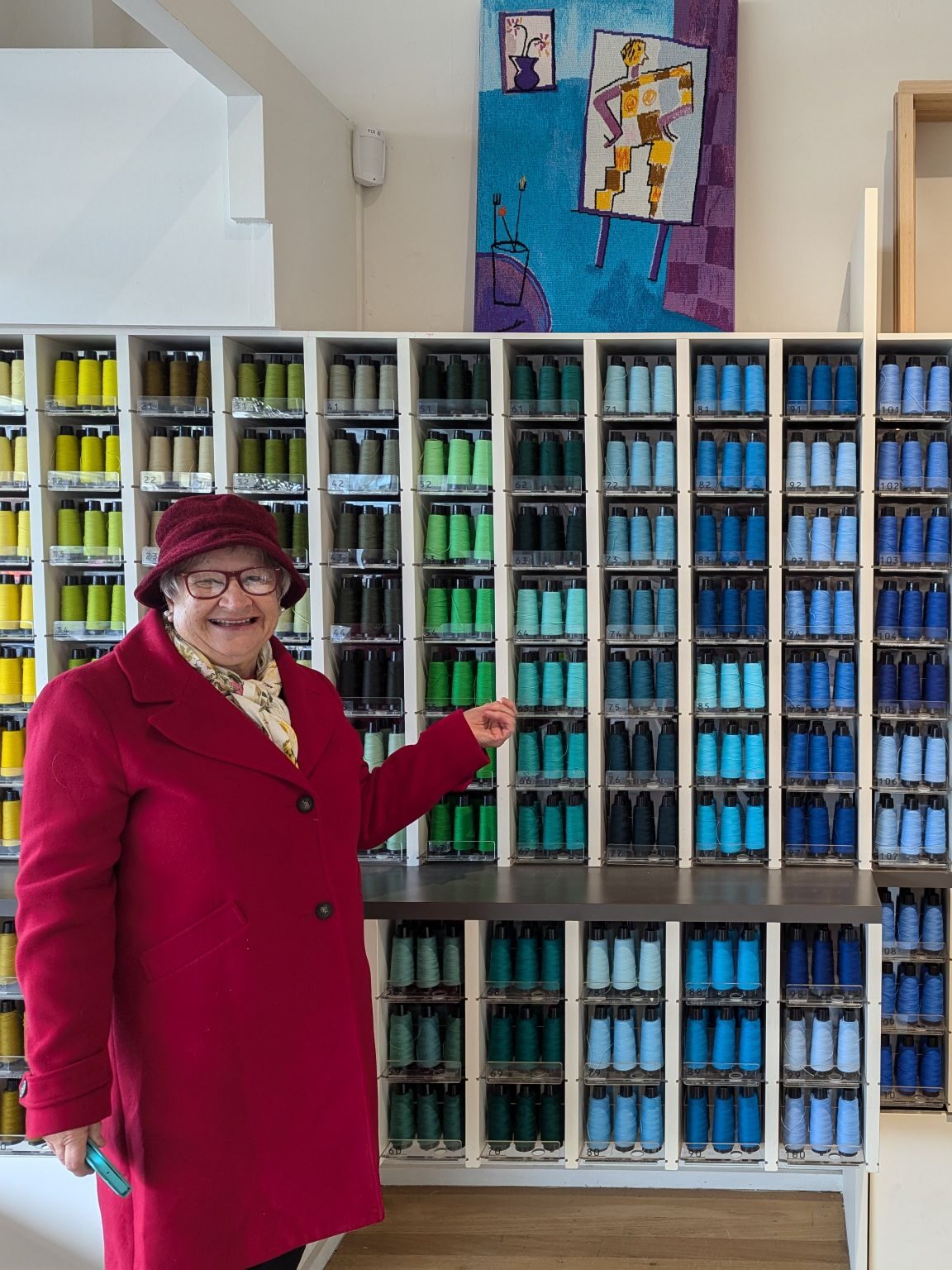 Terrie in front of a large wall of coloured yarn Australia